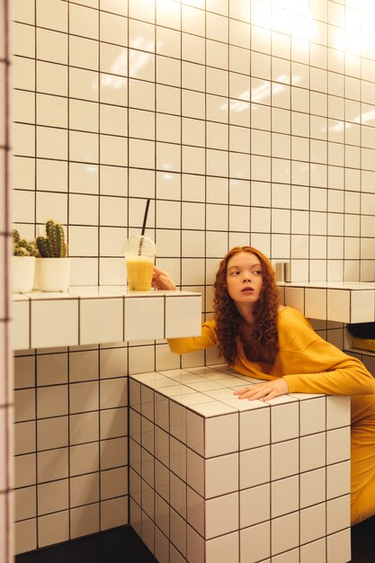 Concentrated young redhead curly lady sitting in cafe