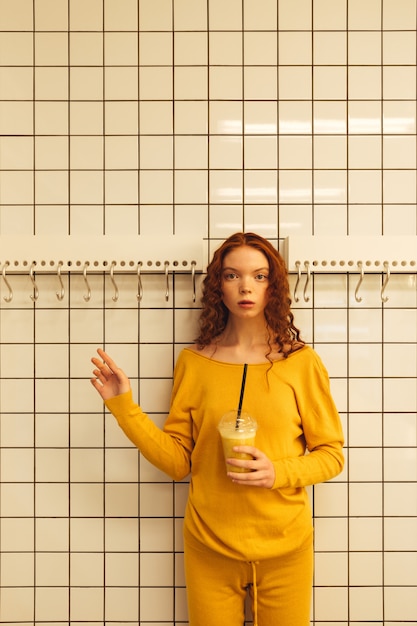 Concentrated young redhead curly lady standing in cafe