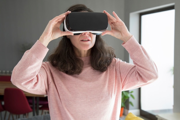 Concentrated young woman adjusting virtual reality goggles