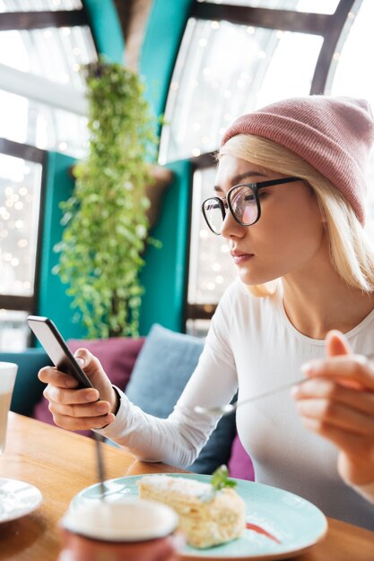 Concentrated young woman using mobile phone in cafe.