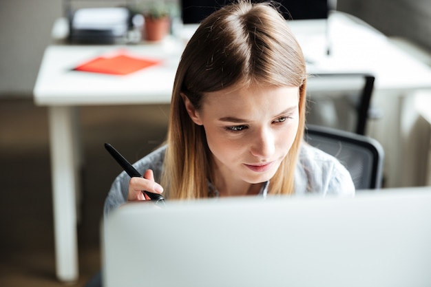 Free photo concentrated young woman work in office using computer