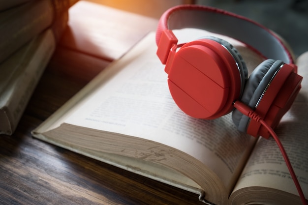 Concept of audiobook. Books on the table with headphones put on them.