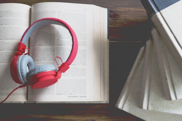 Free photo concept of audiobook. books on the table with headphones put on them.