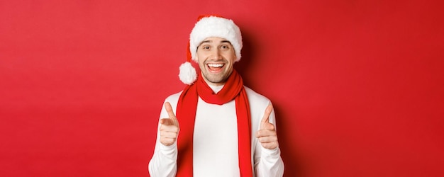 Free photo concept of christmas winter holidays and celebration cheeky man in santa hat and scarf smiling and p