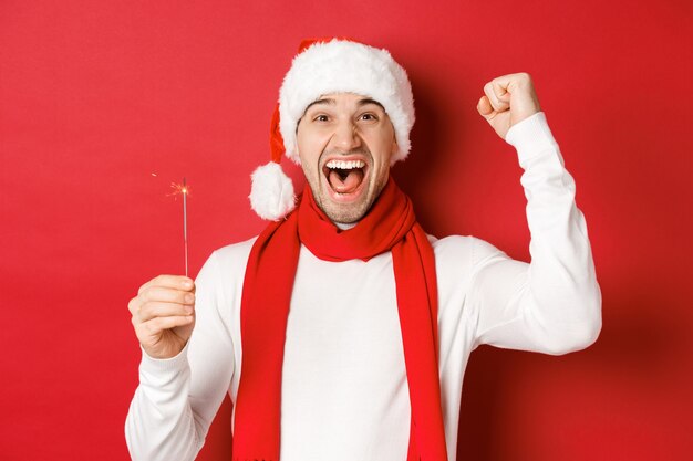 Concept of christmas winter holidays and celebration portrait of excited handsome man raising hand u...