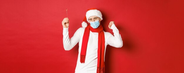 Concept of covid christmas and holidays during pandemic happy man celebrating new year at party wear