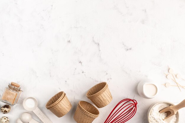 The concept of homemade baking is a whisk for whipping and cupcake molds on a pink background zero waste Copy space