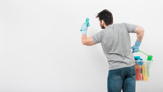 Concept of man cleaning his home with copyspace on wall