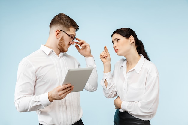 Free photo concept of partnership in business. young emotional man and woman against blue background at studio. human emotions and partnership concept