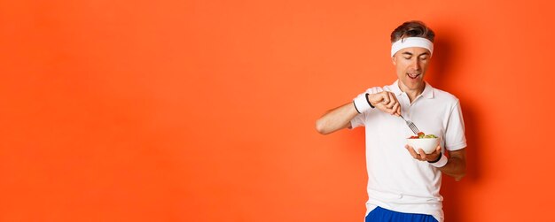 Free photo concept of sport fitness and lifestyle portrait of joyful middleaged guy in workout uniform holding