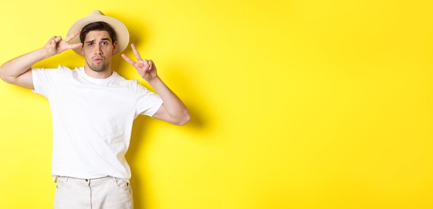 Free photo concept of tourism and vacation cool guy taking photo on holidays posing with peace signs and wearin