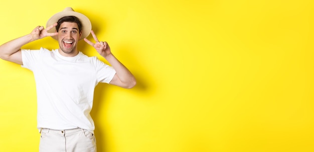 Free photo concept of tourism and vacation happy man tourist posing for photo with peace signs smiling excited