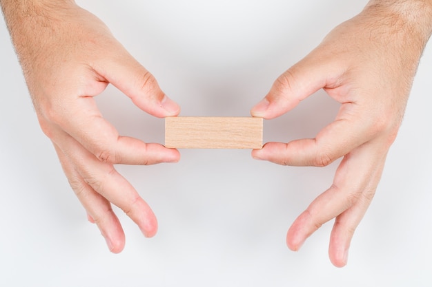 Free photo conceptual of choice man holding wooden label with both hands. on white background top view. horizontal image