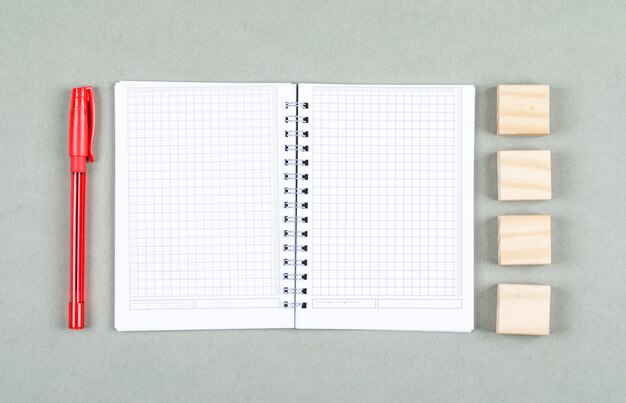 Conceptual of open notebook and taking note. with pen, wooden blocks on gray background top view. space for text horizontal image