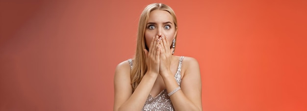 Free photo concerned shocked worried blond woman terrified gasping cover mouth hands pray gesture widen eyes witness terrible accident worry expressing empathy pity standing red background uneasy