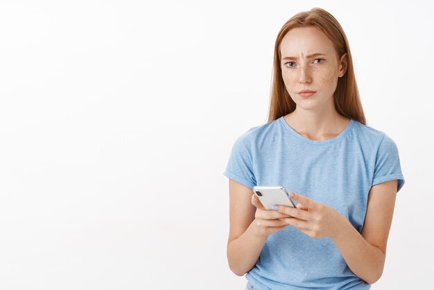 Concerned woman cannot understand sense of message looking questioned and focused frowning, squinting while thinking reconsidering offer, holding smartphone