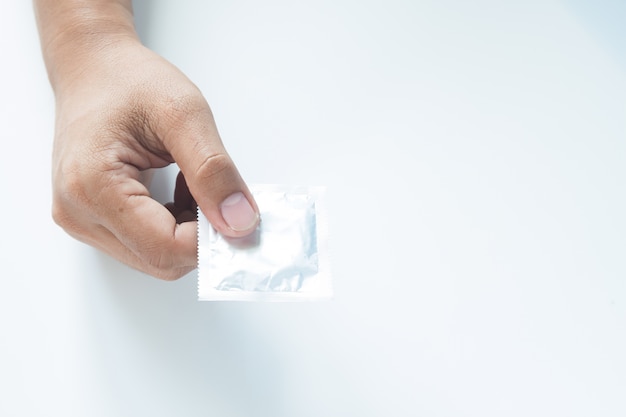 Condom in male hand on white background