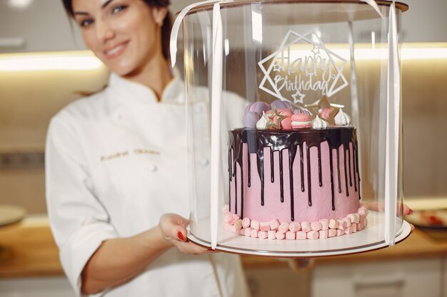 Confectioner in a uniform decorates the cake