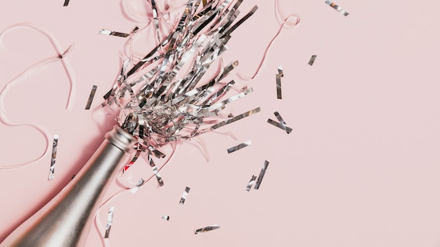 Free photo confetti spilling out of champagne bottle at party