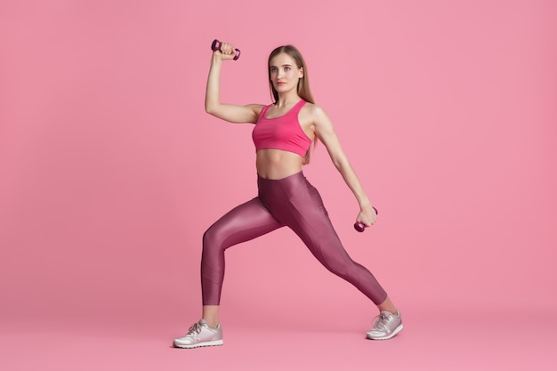 Free photo confidence. beautiful young female athlete practicing in studio, monochrome pink portrait.