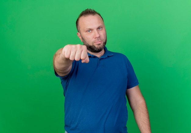 Free photo confident adult slavic man stretching out fist  isolated on green wall with copy space