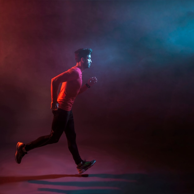 Confident athlete running in dark studio