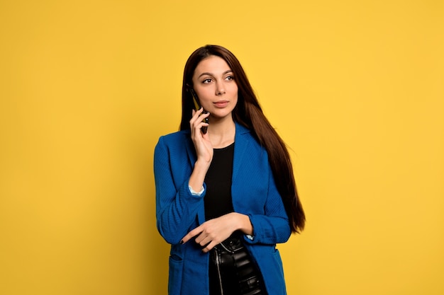 Confident attractive young business woman in blue jacket talking on the phone