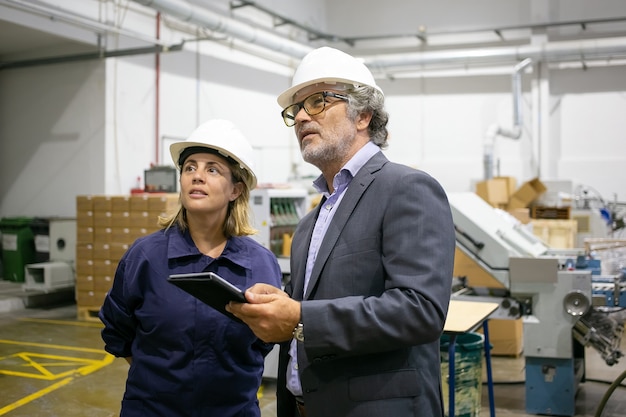 Free Photo confident bearded supervisor talking with female plant worker and holding tablet