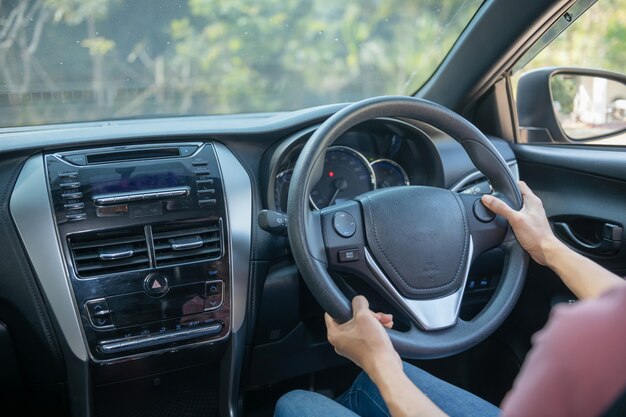 Confident and beautiful. Rear view of attractive young woman in casual wear looking over her shoulder while driving a car. girl holding hand on wheel to handle the car, safety concept.