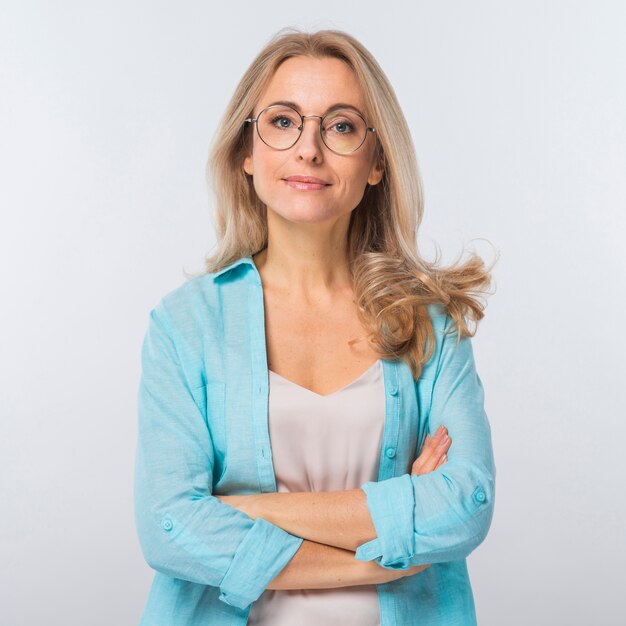 Confident blonde young woman standing with her crossed arms against white background