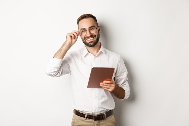 Confident business man working on digital tablet, smiling happy, standing  