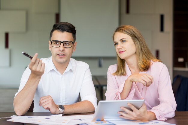 Confident businessman talking to female colleague at briefing. 