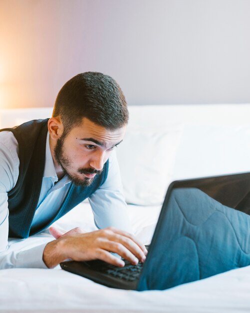 Confident businessman with laptop on bed