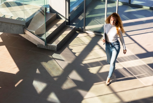 Free photo confident businesswoman walking in the building long shot