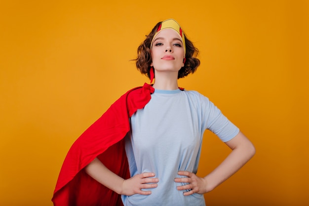 Free photo confident curly girl in superhero attire posing on bright yellow space