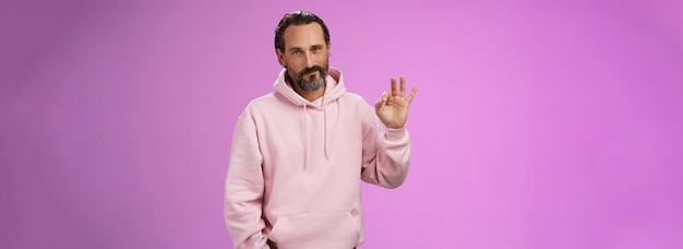 Confident goodlooking lucky old macho guy bearded grey hair in stylish pink hoodie hold hand pocket