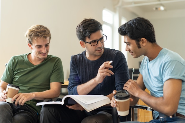 Confident Hispanic guy explaining task to Indian student