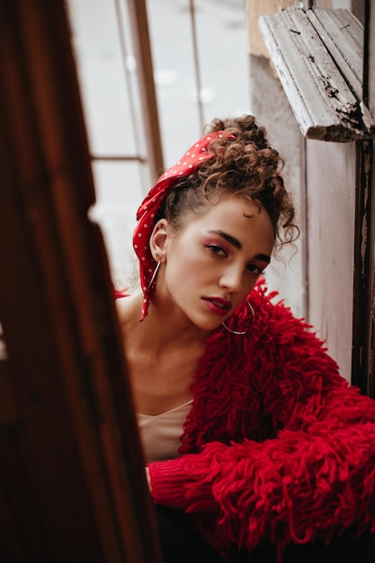 Confident lady in stylish red outfit looks into camera