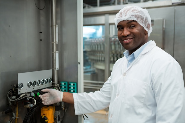 Confident male worker operating machine in juice factory