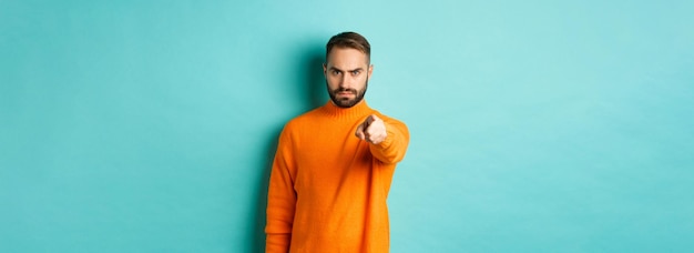 Free photo confident man blame you frowning and pointing finger at camera accuse person judgemental stare stand