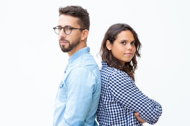 Confident man and woman standing back to back