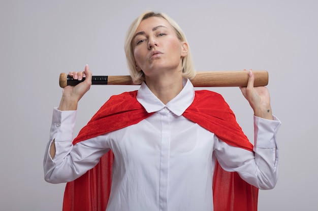 Free photo confident middle-aged blonde superhero woman in red cape holding baseball bat behind neck