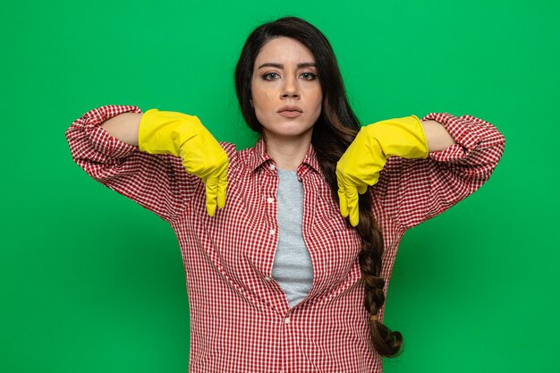 Confident pretty caucasian cleaner woman with rubber gloves pointing down and looking at front