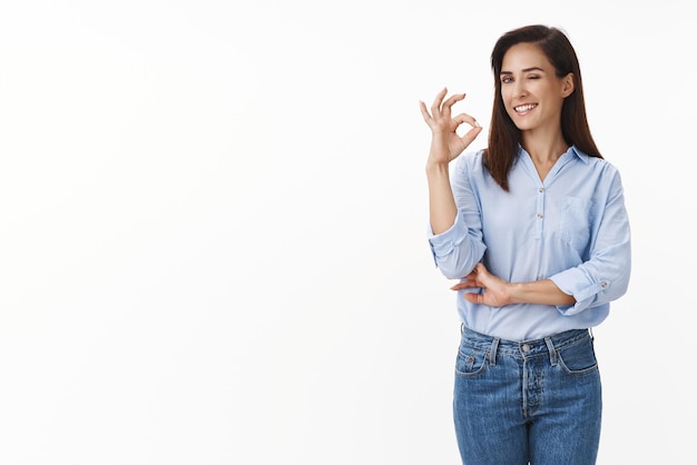 Confident sassy businesswoman have no problems deal any trouble relaxed have business under control wink camera cheeky selfassured show okay ok sign approve choice stand white background