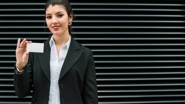 Confident smiling portrait of a smiling young businesswoman showing white business card