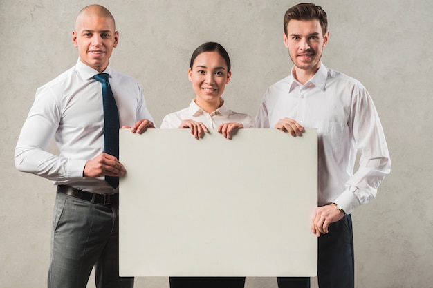 Confident smiling young businesswoman with his two colleagues holding blank placard