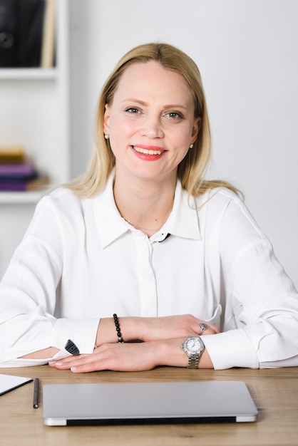 Free Photo confident smiling young businesswoman with laptop on table