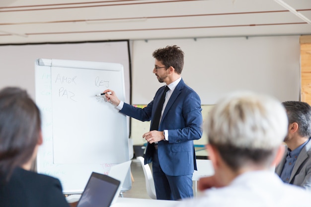 Free photo confident speaker in eyeglasses talking near whiteboard