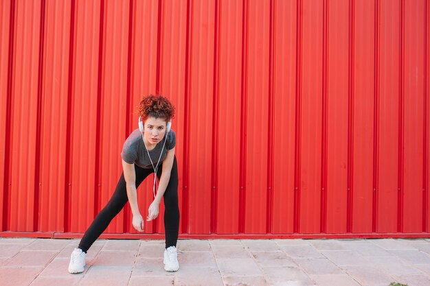 Confident sportswoman in earphones posing at camera