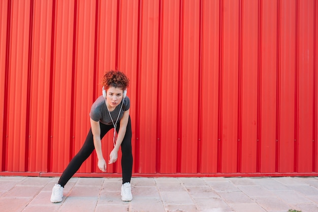 Confident sportswoman in earphones posing at camera